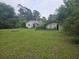 Wide backyard with a home, garage, lawn, and lush trees at 207 Cedar St, Saint George, SC 29477