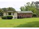 Exterior view of backyard featuring spacious lawn, deck, brick exterior, and mature trees at 2163 Pinehurst Ave, Charleston, SC 29414