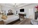 Bright main bedroom features modern tray ceiling, wood floors, stylish furniture, and en-suite bathroom access at 228 Lucca Dr, Summerville, SC 29486