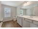 A bright bathroom with double sinks, shaker cabinets, light countertops, and a large mirror at 242 Torslanda Ln, Summerville, SC 29486