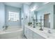 This bright, blue bathroom features double sinks, a large mirror, and a soaking tub under a window at 300 Foxglove Ave, Summerville, SC 29483