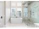 Bright bathroom featuring a soaking tub under shuttered windows and a glass-enclosed shower with marble tiling at 34 Eugenia Ave # B, Kiawah Island, SC 29455