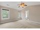 Large carpeted bedroom with ceiling fan and windows, door to adjoining bathroom suite at 3588 Bagley Dr, Mount Pleasant, SC 29466