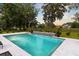 Backyard pool features a modern design with a waterfall feature, surrounded by lush landscaping and mature trees at 4246 Club Course Dr, North Charleston, SC 29420