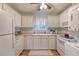 A full kitchen featuring white appliances and cabinets with a window above the sink and light from a ceiling fan at 516 Arlington Dr # B4, Charleston, SC 29414
