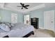 A well-lit main bedroom with a tray ceiling, ceiling fan, and a view into the adjoining living space at 5541 Alpine Dr, Summerville, SC 29483