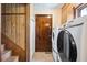 Functional laundry area features modern machines, a wooden door, and stairs with classic wood paneling at 107 Salina Ln, Goose Creek, SC 29445