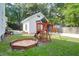 Backyard playground featuring wooden playset with slide, swings, and a sandbox amid lush greenery at 1151 Camellia Dr, Mount Pleasant, SC 29464