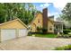 Charming yellow home featuring a brick chimney, inviting front porch, and detached two-car garage at 127 White Pine Way, Summerville, SC 29485