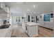 Open concept kitchen with white cabinets, quartz countertop island and stainless steel appliances adjacent to the living area at 1384 Locals St, Summerville, SC 29485