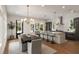 Open kitchen with stainless appliances, an island, and bar stool seating flows into dining area with contemporary lighting at 1405 Mataoka St, Mount Pleasant, SC 29464