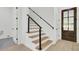 Modern staircase with wood treads, black metal railing, and natural light filtering through a nearby door at 142 Argosy Dr, Summerville, SC 29483
