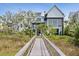 View of the back of the luxury house featuring a boardwalk, backyard and professional landscaping at 156 Nobels Point St, Charleston, SC 29492