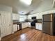 Modern kitchen boasts stainless steel appliances, white cabinetry, laminate countertops, and wood flooring at 1705 Falcon Cove Ln, Hanahan, SC 29410