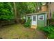 View of a green garden shed with a white door, surrounded by lush plants and a grassy area at 173 Fishburne St, Charleston, SC 29403