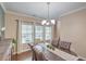 Bright dining room with a wood table, six chairs, a chandelier, and three windows dressed with white curtains at 202 Center Hill Ct, Summerville, SC 29485