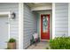 Stylish front entrance with a vibrant red door, charming decor, and well-maintained landscaping at 259 Camber Rd, Huger, SC 29450
