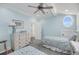 Light blue bedroom with two twin beds, a ceiling fan, natural light from a round window and classic decor at 3126-B Palmetto Blvd # 4, Edisto Island, SC 29438