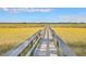 Picturesque marsh view featuring a wooden boardwalk leading to a serene nature preserve under a clear blue sky at 3152 Riverine, Charleston, SC 29414