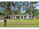 Charming white brick home featuring black shutters and door, manicured landscaping, and a covered parking area at 403 Wedgewood St, Charleston, SC 29407