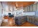 Rustic kitchen with wooden cabinets, a center island with bar stools, and adjacent living area with wood ceiling at 405 Palmetto Blvd, Edisto Island, SC 29438