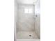 Walk-in shower featuring marble-style tiling, a rain shower head, and a unique patterned tile floor design at 405 Palmetto Blvd, Edisto Island, SC 29438