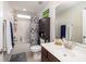 Well-lit bathroom features a shower-tub combo, neutral tile flooring, and wooden vanity with framed mirror at 4953 W Liberty Park Cir, North Charleston, SC 29405