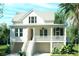 Inviting two-story home boasts a metal roof, covered front porch, and a beautifully landscaped yard with native palm trees at 5005 Saltspray Ln, Johns Island, SC 29455