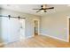 Bright bedroom with hardwood floors, barn door to bath, walk-in closet, and modern ceiling fan at 54 Summer Dr, Walterboro, SC 29488