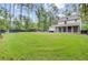 Spacious backyard featuring lush lawn, mature trees, privacy fence, patio, and screened porch at 6190 Button Bush Dr, Ravenel, SC 29470
