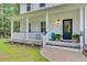 Inviting front porch with white columns, stylish decor, and a well-manicured garden bed, creating a warm entry at 6190 Button Bush Dr, Ravenel, SC 29470