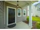 Inviting front porch featuring a black door, modern light fixture, and well-maintained landscaping at 716 Mcroy St, Moncks Corner, SC 29461