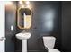 Modern powder room with dark walls, stylish mirror, pedestal sink, and toilet at 716 Mcroy St, Moncks Corner, SC 29461