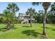 Expansive backyard view with lush green lawn and tall palm trees surrounding this charming home at 8964 Palmetto Rd, Edisto Island, SC 29438