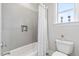 Bright bathroom with gray tile, shower-tub combo, and a window providing natural light at 8964 Palmetto Rd, Edisto Island, SC 29438