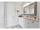 Light filled bathroom with white cabinets, marble countertops, and a decorative mirror at 8964 Palmetto Rd, Edisto Island, SC 29438