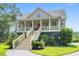 Charming two-story home with a grand staircase, columns, and red door, nestled in a lush landscape at 8964 Palmetto Rd, Edisto Island, SC 29438