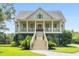Two-story home with a covered porch, stairs, and a manicured lawn at 8964 Palmetto Rd, Edisto Island, SC 29438