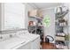 Bright laundry room with modern washer and dryer, storage shelves, and window with natural light at 8964 Palmetto Rd, Edisto Island, SC 29438