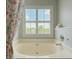 Well-lit bathroom featuring a garden tub and window with plantation shutters at 113 Rockdale Ln, Goose Creek, SC 29445