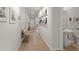 Long hallway with light wood floors, art display and white paint that leads to the home's entryway at 1150 Cooper Point St, Summerville, SC 29485