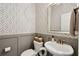 Stylish powder room features patterned wallpaper, wainscoting, white fixtures, and modern decor at 1164 Sharpestowne Ct, Mount Pleasant, SC 29466