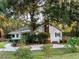 Charming white home with brick chimney and a covered porch surrounded by lush greenery and mature trees at 1351 Winifred St, Mount Pleasant, SC 29464