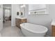 Bathroom with modern soaking tub, wood vanity, neutral tile floor, and an open doorway to the bedroom at 1535 Low Pk St, Mount Pleasant, SC 29464