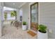 Charming front porch with brick flooring, seating, potted plants, and a decorative wooden door at 1535 Low Pk St, Mount Pleasant, SC 29464