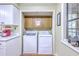 A compact laundry room with a washer and dryer, cabinets, and a bright window at 18 Indigo Ln, Goose Creek, SC 29445