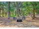 Wooded backyard featuring mature trees and a fire pit with chairs and table at 18 Tupelo Trl, Edisto Island, SC 29438