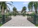 Inviting brick driveway leads to a beautiful home, framed by lush landscaping and ornamental palms at 210 Ocean Blvd, Isle of Palms, SC 29451