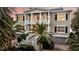 Charming two-story home with a welcoming front porch, set amidst lush tropical landscaping at 210 Ocean Blvd, Isle of Palms, SC 29451