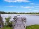Lake view with a wooden dock and bench, under a partly cloudy sky with trees in the distance at 2206 Weepoolow Trl, Charleston, SC 29407